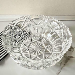 Peut inclure: Un bol en verre taill&eacute; transparent avec un motif g&eacute;om&eacute;trique d&eacute;taill&eacute;. Le bol pr&eacute;sente un motif en &eacute;toile au centre et un bord festonn&eacute;. Le bol est probablement utilis&eacute; pour servir ou exposer.