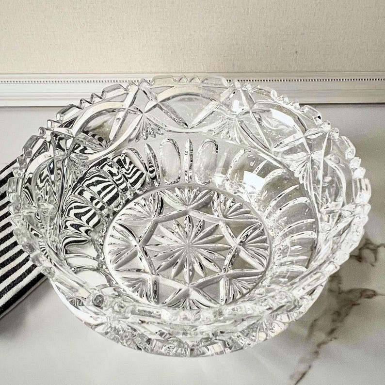 Peut inclure: Un bol en verre taill&eacute; transparent avec un motif g&eacute;om&eacute;trique d&eacute;taill&eacute;. Le bol pr&eacute;sente un motif en &eacute;toile au centre et un bord festonn&eacute;. Le bol est probablement utilis&eacute; pour servir ou exposer.