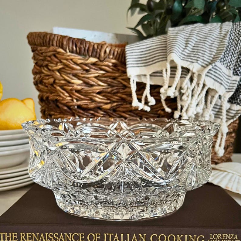 Peut inclure: Un saladier en verre taill&eacute; transparent avec un motif g&eacute;om&eacute;trique. Le saladier est pos&eacute; sur un livre intitul&eacute; "The Renaissance of Italian Cooking". Un panier en osier et une serviette ray&eacute;e sont en arri&egrave;re-plan.