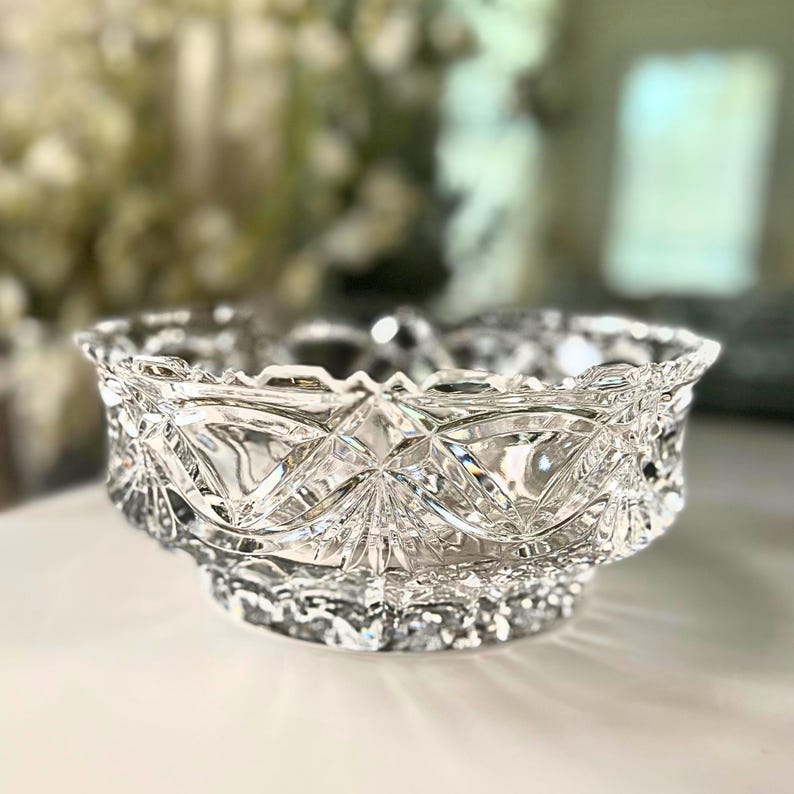Peut inclure: Un bol en verre taill&eacute; transparent avec un motif g&eacute;om&eacute;trique d&eacute;taill&eacute;. Le bol a un bord festonn&eacute; et une base en pi&eacute;destal. Le design complexe refl&egrave;te la lumi&egrave;re, cr&eacute;ant un effet scintillant. Ce bol d&eacute;coratif convient au service ou &agrave; l'exposition.
