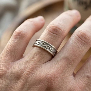 Puede incluir: Una taza de cerámica blanca con un asa negra y el texto "But First, Coffee" en negrita negra. La taza está sobre una superficie de madera. La taza mide aproximadamente 10 cm de alto.