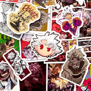 Puede incluir: Una colecci&oacute;n de pegatinas de estilo anime con varios personajes y dise&ntilde;os. Las pegatinas muestran una gama de colores, incluyendo rojo, blanco y negro, con ilustraciones detalladas y contornos audaces. Algunas pegatinas tienen texto.