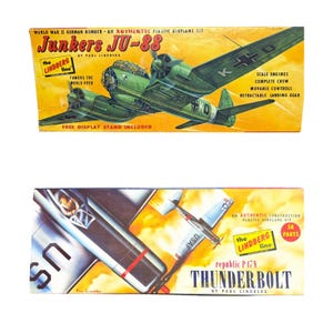 Op de afbeelding: Twee vintage modelvliegtuigkits. De bovenste doos toont een groene Junkers JU-88 Duitse bommenwerper met de tekst "World War II German Bomber". De onderste doos toont een zilveren Republic P-47N Thunderbolt met "USAF" aan de zijkant.
