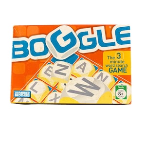 May include: Boggle word search game box with the word "BOGGLE" in blue letters on an orange background. The box includes letter dice and the text "The 3 minute word search GAME". Ages 8+.