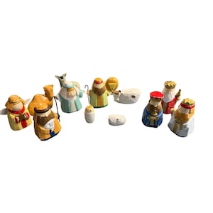May include: A wooden nativity set featuring figures of the Holy Family, the Three Wise Men, angels, and animals. The figures are painted in various colors, including gold, blue, red, and green. The set is designed for display during the Christmas season.