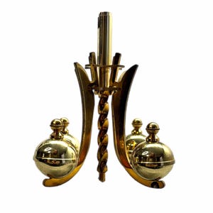 May include: A gold-colored chandelier with a central twisted column and curved arms. The chandelier has four spherical ornaments and a decorative top. The design is symmetrical and features a polished finish, reflecting light.