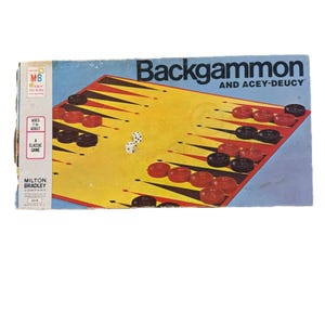 May include: A vintage Milton Bradley Backgammon game set. The game board is yellow with red and black triangles, and the box is blue. The set includes red and black game pieces and dice. The box reads "Backgammon and Acey-Deucy".