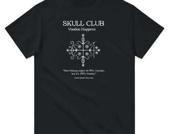 May include: Black t-shirt with white text and graphic. The text reads "SKULL CLUB Voodoo Happens." Below the text is a white graphic design. The bottom of the shirt has the text "New Orleans might be 90% Catholic, but it's 100% Voodoo." and "www.skull-club.com."