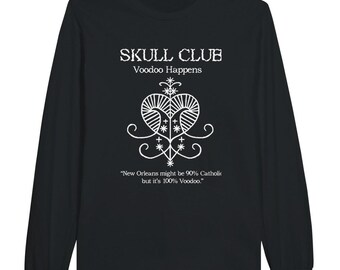 May include: Black long-sleeve shirt with white text and graphic. The text reads "SKULL CLUB Voodoo Happens." Below the graphic, the text reads "New Orleans might be 90% Catholic but it's 100% Voodoo."