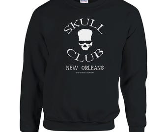 May include: Black sweatshirt with a white graphic that reads "SKULL CLUB" above a skull image and "NEW ORLEANS" below. The website address www.skull-club.com is also printed on the sweatshirt. The sweatshirt is made of a soft material.