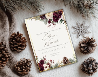 May include: A wedding invitation with a gold border, featuring the names Ethan and Sarah, and the date December 07 at 2 PM. The invitation is decorated with burgundy and white floral arrangements and pine cones. A silver snowflake and pine needles are also present.