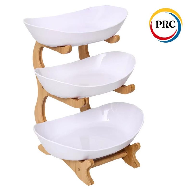 May include: A three-tiered serving stand featuring three white, oval-shaped bowls supported by a light-colored wooden frame. The structure has a curved design with wooden supports holding each bowl in place. A circular logo with the text PRC is visible.