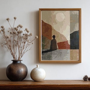 Puede incluir: Impresión artística enmarcada con una silueta humana abstracta, en tonos tierra. La obra de arte está en un marco de madera. Un jarrón marrón oscuro con flores secas y un jarrón esférico blanco están sobre una superficie de madera.