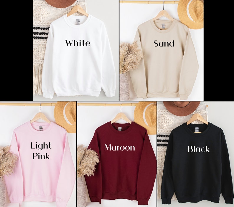 May include: Five crewneck sweatshirts in different colors: white, sand, light pink, maroon, and black. Each sweatshirt has a simple, bold text design on the front. The text reads "White", "Sand", "Light Pink", "Maroon", and "Black".