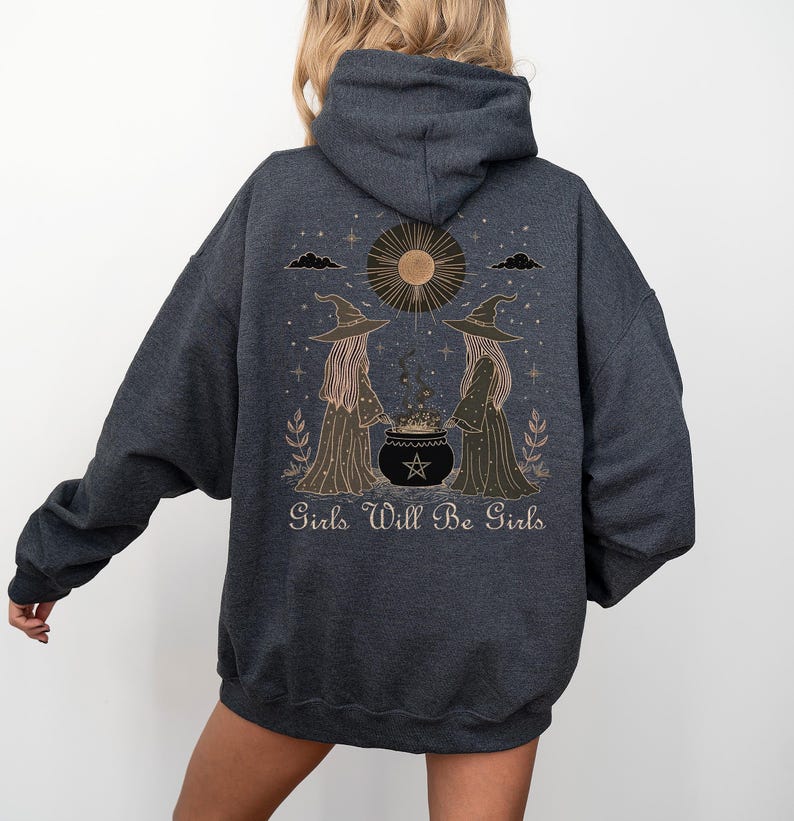 Pu&ograve; includere: Felpa con cappuccio grigio scuro con una grafica di due streghe, un calderone, un sole e la scritta "Girls Will Be Girls". Il design &egrave; nei toni del marrone e dell'oro. La felpa ha un cappuccio e maniche lunghe.