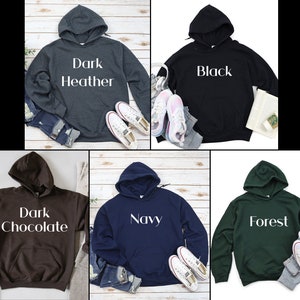 Pu&ograve; includere: Cinque felpe con cappuccio in diversi colori: grigio scuro melange, nero, cioccolato scuro, blu navy e verde bosco. Ogni felpa ha un'etichetta di testo bianca sul davanti con il nome del colore.