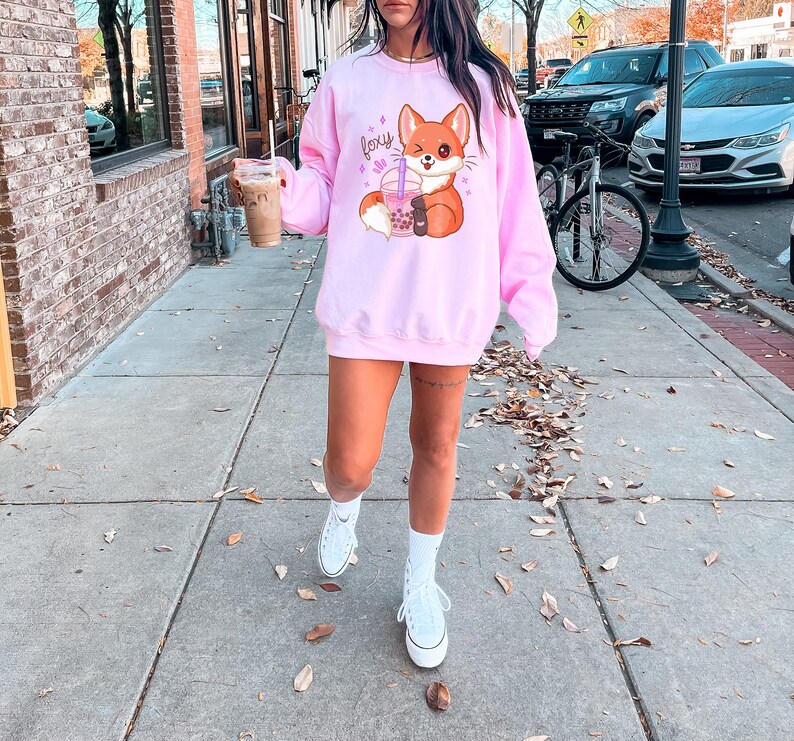 May include: Pink sweatshirt with a cartoon fox holding a boba tea and the word "foxy" in pink glitter letters.