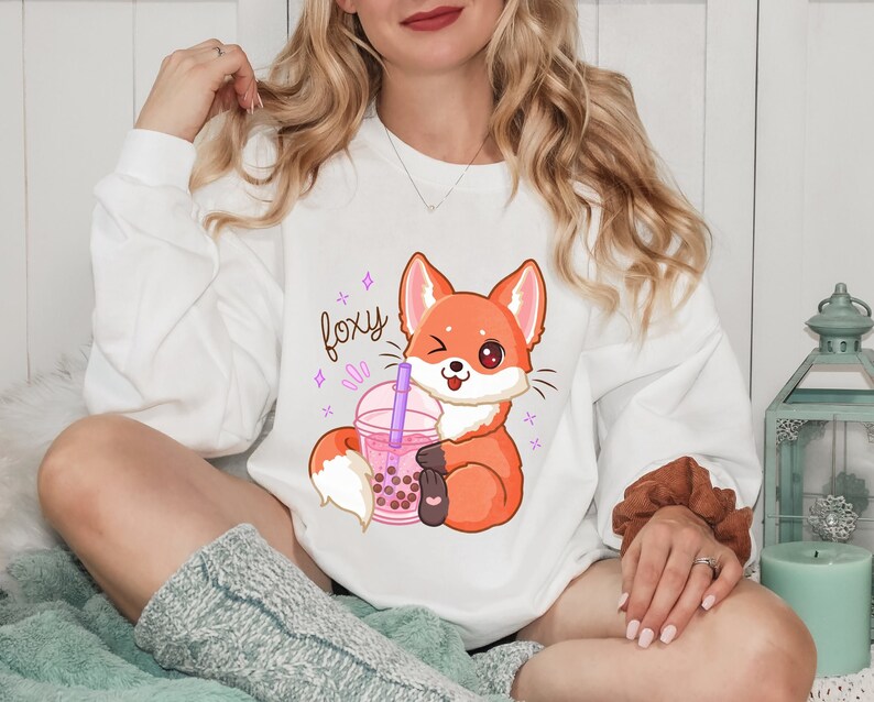 May include: White sweatshirt with a cartoon fox holding a boba tea cup. The text "foxy" is printed on the sweatshirt.