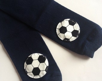 May include: A pair of navy blue leg warmers with white and black soccer ball patches on each knee.