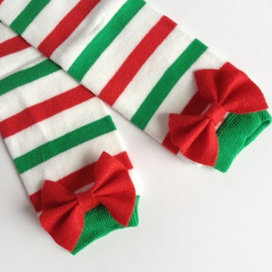 May include: A pair of red and green striped leg warmers with red felt bows at the bottom.