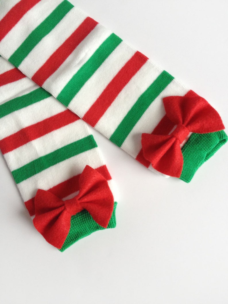 May include: A pair of red and green striped leg warmers with red felt bows at the bottom.