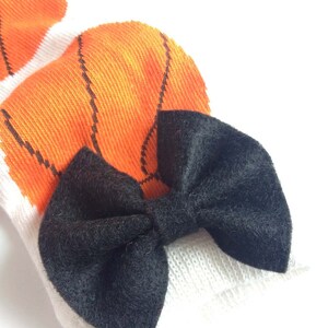 Puede incluir: Un lazo de terciopelo negro atado en un par de calcetines blancos con dise&ntilde;os de baloncesto naranja.