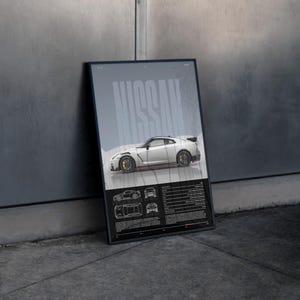 May include: A framed poster featuring a white Nissan sports car with yellow brake calipers. The word "NISSAN" is displayed in large, stylized letters. Below the car are technical drawings and text.