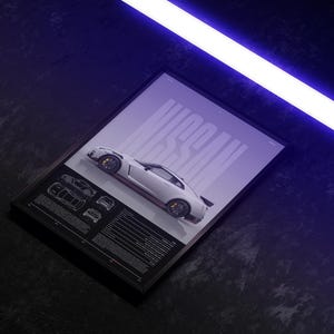 May include: Framed print of a white Nissan sports car with red detailing. The word "NISSAN" is displayed in large letters. Below the car are technical drawings and specifications. The background is a gradient of dark blue and purple.