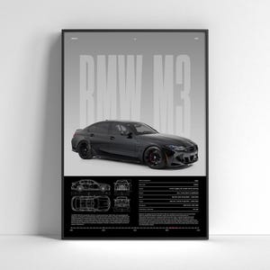 Op de afbeelding: Een ingelijste poster met een zwarte BMW M3. De poster toont de naam van de auto in grote, grijze letters, samen met technische tekeningen en specificaties. De auto is afgebeeld in een strakke, donkere kleur.