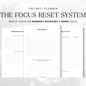 May include: A set of three white paper pages with the text "THE FOCUS RESET SYSTEM" and "GENTLE TOOLS FOR BURNOUT RECOVERY & ADHD FOCUS". The pages include sections for a to-do list, weekly wins, and self-reflection prompts. The bottom right corner has the initials "mws".