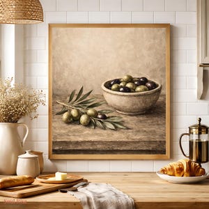 May include: A framed still life painting of olives. The painting features a rustic bowl filled with green and black olives, olive branches, and a wooden table. The painting is in a wooden frame.