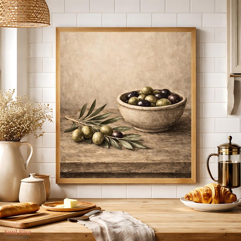 May include: A framed still life painting of olives. The painting features a rustic bowl filled with green and black olives, olive branches, and a wooden table. The painting is in a wooden frame.