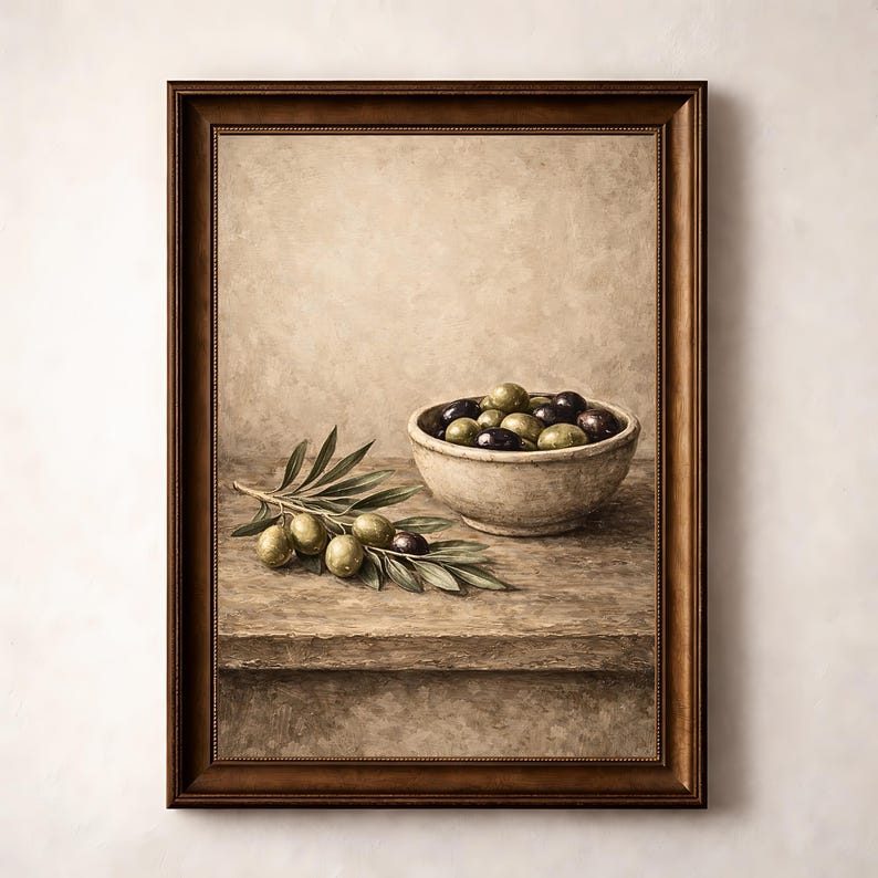 May include: A framed still life painting featuring a rustic wooden table with a bowl of olives and a sprig of olive branches. The olives are a mix of green and dark purple, and the bowl is a light beige color. The painting has a warm, neutral color palette.