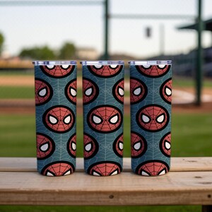 Peut inclure: Trois gobelets en acier inoxydable avec un motif Spider-Man. Le motif pr&eacute;sente le masque du personnage en rouge et blanc, sur un fond bleu sarcelle avec un motif de toile d'araign&eacute;e. Les gobelets sont cylindriques et ont des couvercles argent&eacute;s.