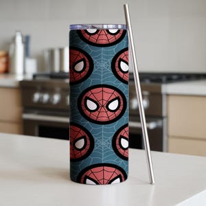 Peut inclure: Un gobelet cylindrique et haut avec un motif r&eacute;p&eacute;t&eacute; du masque de Spider-Man sur un fond bleu sarcelle avec des toiles d'araign&eacute;es blanches. Une paille en m&eacute;tal argent&eacute; est plac&eacute;e &agrave; c&ocirc;t&eacute; du gobelet. Le gobelet est con&ccedil;u pour les boissons froides.