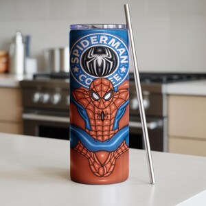 May include: A stainless steel tumbler featuring a Spider-Man design. The tumbler has a blue top with the words "Spider-Man Coffee" and a spider logo. The body of the tumbler displays Spider-Man's costume in red and blue. A silver straw is placed next to the tumbler.