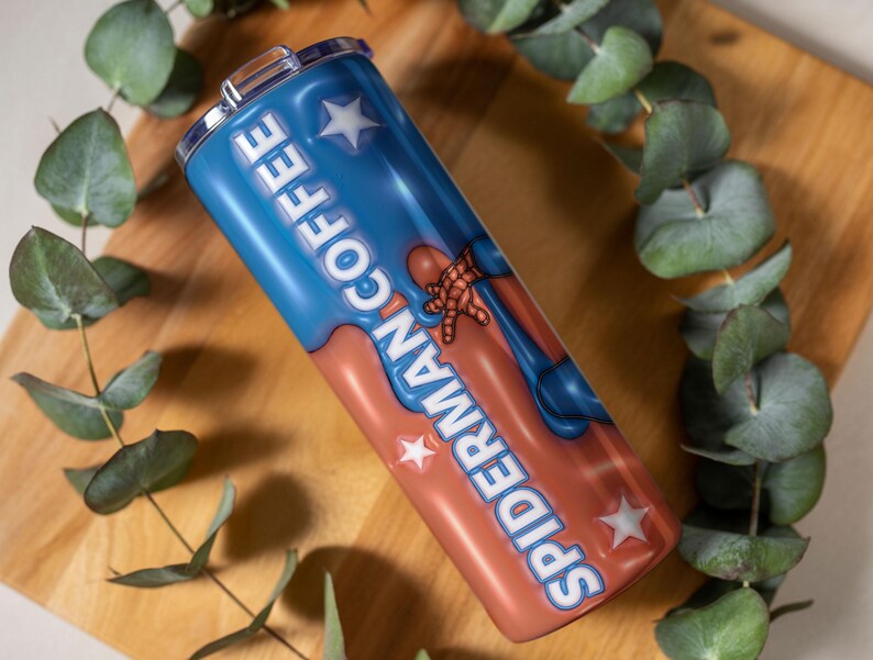 May include: A stainless steel tumbler with a blue and red design featuring the words "COFFEE" and "SPIDERMAN" in white. The tumbler has a silver lid and is decorated with white stars and a Spiderman graphic.