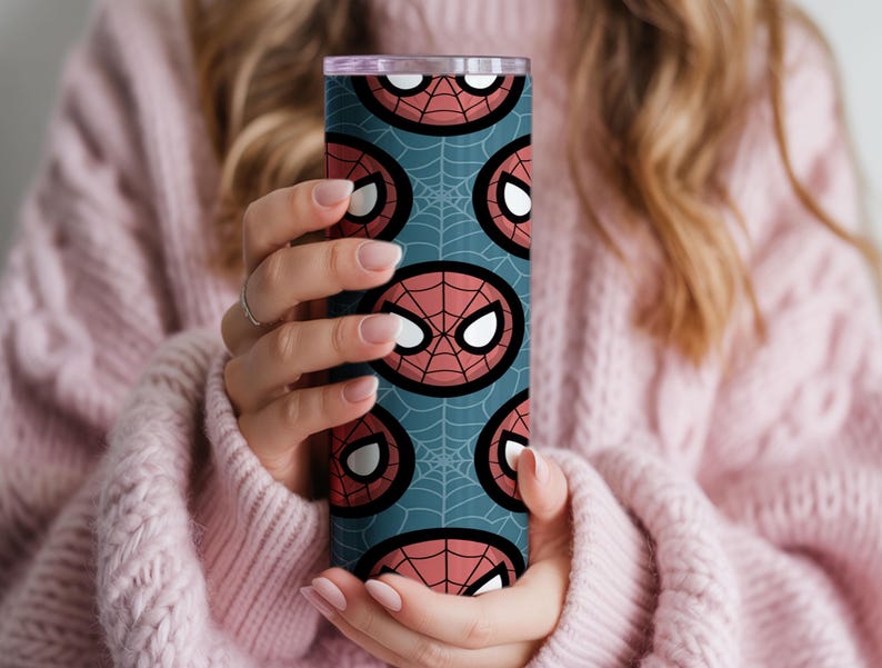 Peut inclure: Un gobelet cylindrique et haut avec un motif r&eacute;p&eacute;t&eacute; du masque de Spider-Man sur un fond bleu sarcelle. Le masque est rouge avec des yeux blancs et un contour noir, sur un motif de toile d'araign&eacute;e.