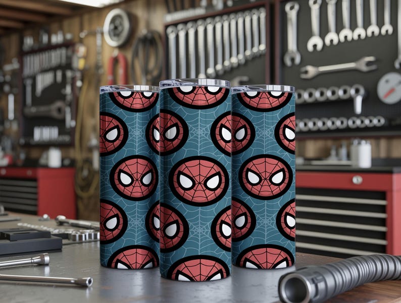 Peut inclure: Trois gobelets en acier inoxydable avec un motif r&eacute;p&eacute;t&eacute; du masque de Spider-Man sur un fond bleu-vert. Le motif pr&eacute;sente le masque en rouge, noir et blanc, avec un motif de toile d'araign&eacute;e. Les gobelets sont cylindriques et ont un bord argent&eacute;.