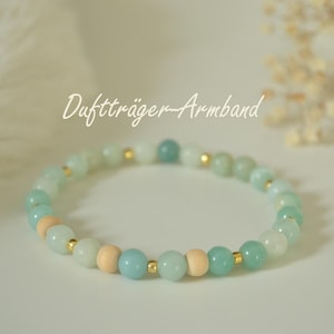 Könnte beinhalten: Ein Armband mit hellgrünen, blauen und Holzperlen. Das Armband hat goldfarbene Abstandshalter und den Text "Duftträger-Armband" in einer Schreibschrift.