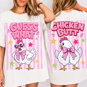 May include: White t-shirt with a playful design featuring a cartoon chicken wearing sunglasses and a bow tie. The front of the shirt says "Guess What" in pink letters. The back of the shirt says "Chicken Butt".