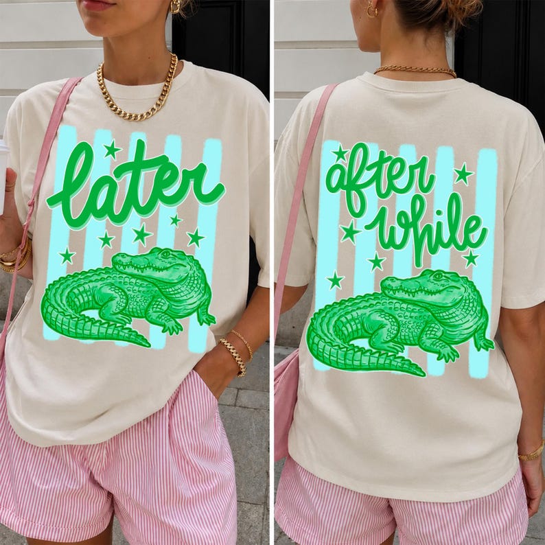 May include: Cream-colored t-shirt with a green alligator graphic and the word "later" in green script. The design includes light blue stripes and green stars. The back of the shirt says "after while" with the same design.