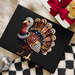 May include: A black canvas featuring a turkey design crafted from multi-colored rhinestones. The turkey displays a fan-shaped tail with amber, brown, and clear crystals, a red wattle, and a body composed of dark blue, red, and white faceted gems.