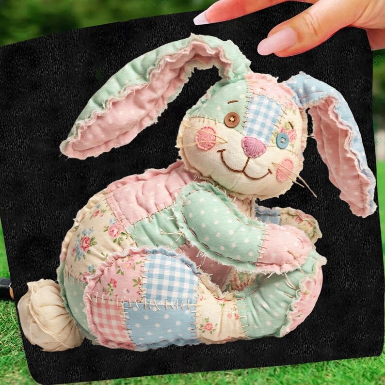 May include: A patchwork bunny plush toy in pastel colors. The bunny features a mix of floral, polka dot, and gingham patterns in pink, blue, and green. It has button eyes, a stitched smile, and long, floppy ears.