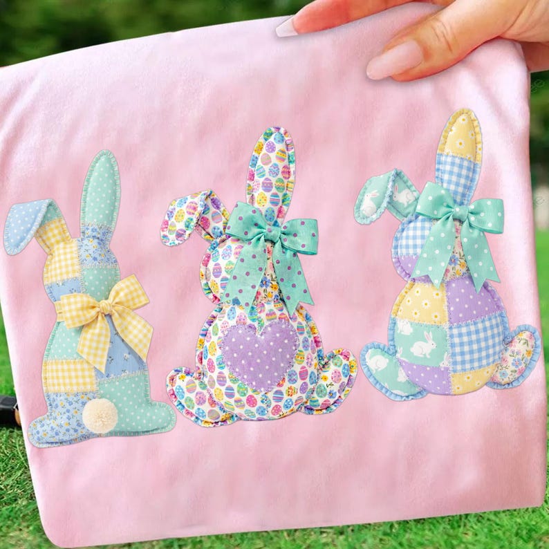 May include: Three colorful patchwork bunny decorations on a pink background. Each bunny has a different pattern, including polka dots, gingham, and floral prints. They are adorned with bows and a pom-pom tail. The bunnies are perfect for Easter.
