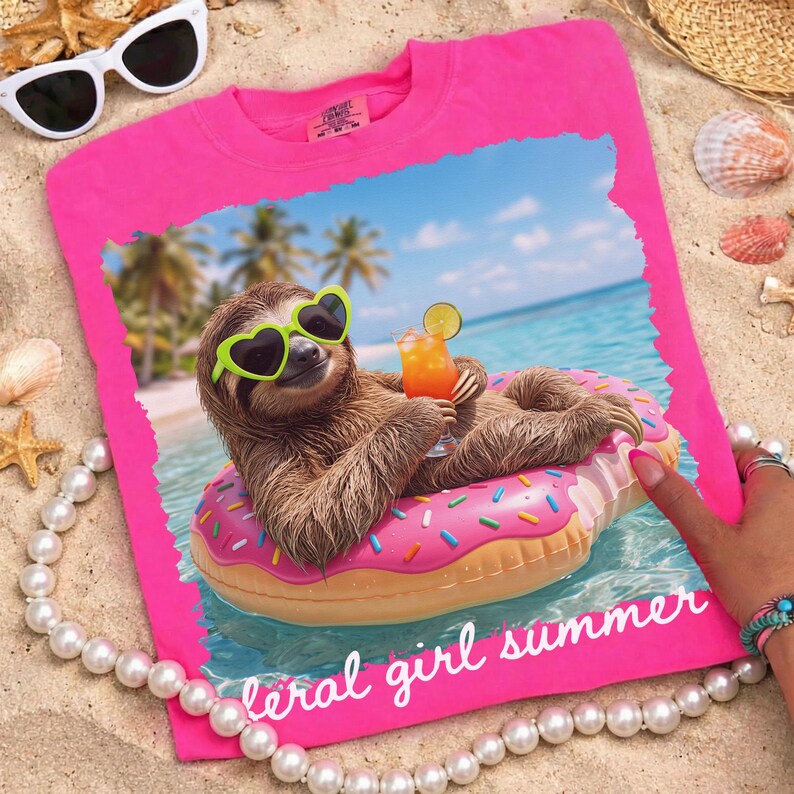 May include: Hot pink t-shirt featuring a sloth wearing heart-shaped sunglasses and floating on a donut-shaped floatie in the ocean. The sloth is holding a tropical drink. Text on the shirt reads "feral girl summer".