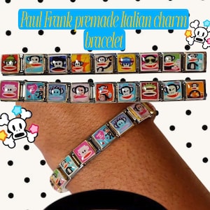 Op de afbeelding: Een kant-en-klare Italiaanse bedelarmband van Paul Frank met een reeks metalen schakels, elk met een kleurrijke afbeelding van het Julius-aapfiguurtje in verschillende houdingen en outfits, tegen een witte achtergrond met zwarte stippen.