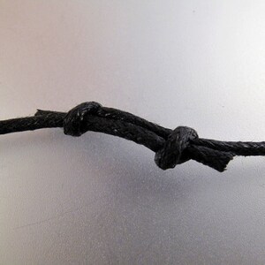 May include: A close-up of a black cord tied in a knot.