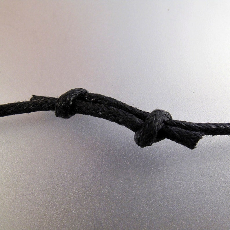 May include: A close-up of a black cord tied in a knot.