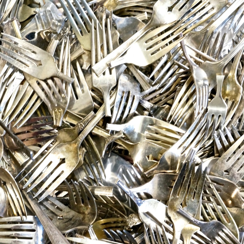 May include: A large pile of silver forks, all jumbled together. The forks are all different sizes and styles, but they are all made of the same metal.
